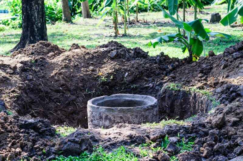 Un drain est exposé dans un trou dans une cour.