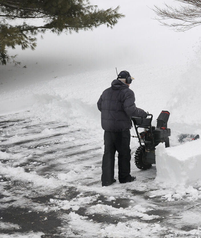 L'homme souffle des rangées de neige dans l'allée.