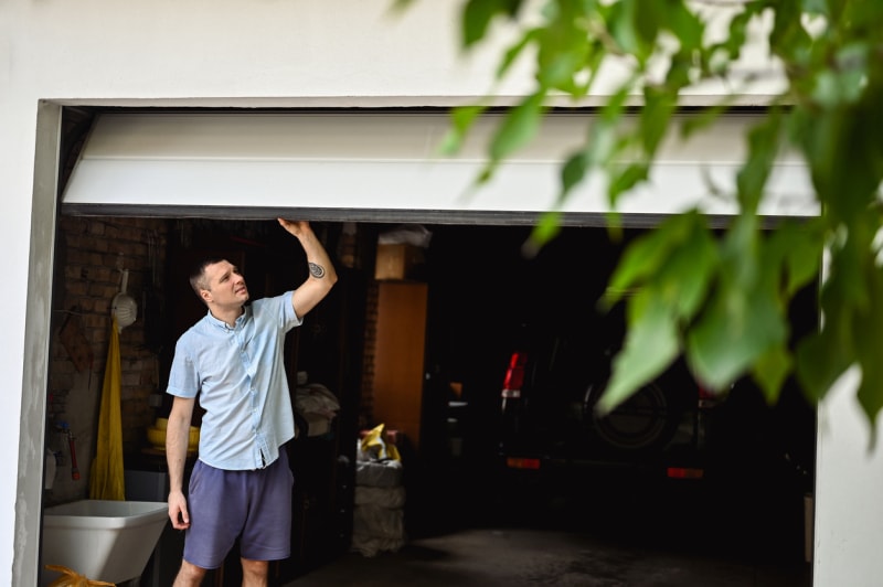 Un jeune homme portant une chemise blanche et un short bleu traverse un garage attenant.