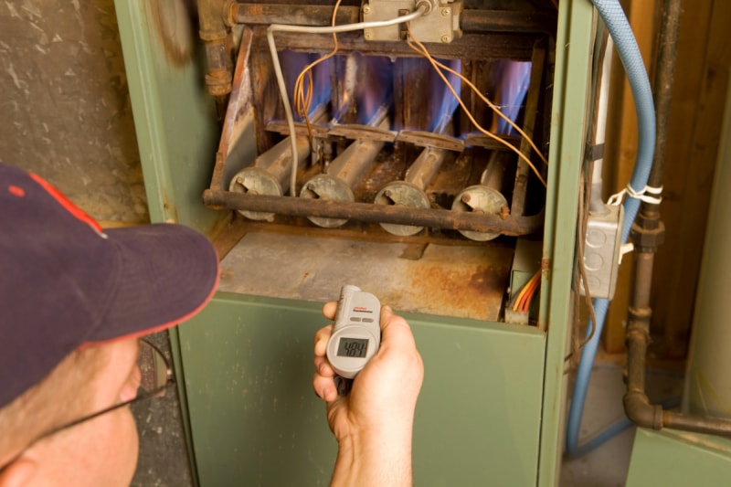 Personne vérifiant la température sur la veilleuse du four à gaz.