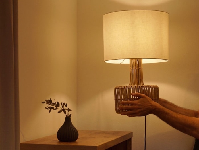 Personne plaçant une lampe avec une lumière tamisée sur une table.