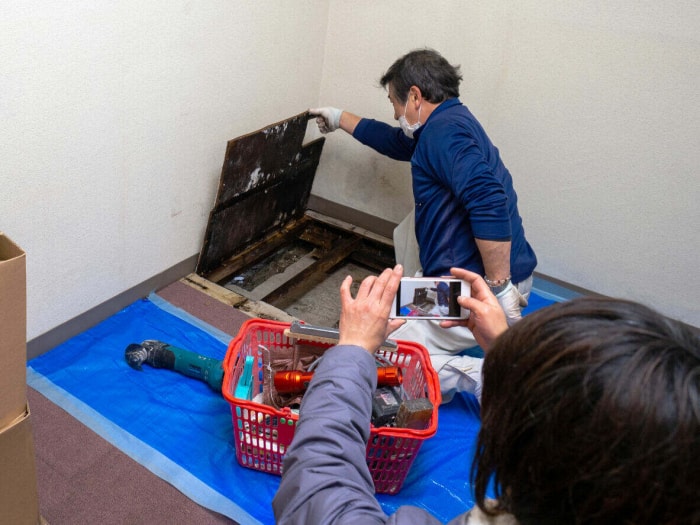 Contremaître prenant une photo pendant qu'un ouvrier du bâtiment enlève le plancher.