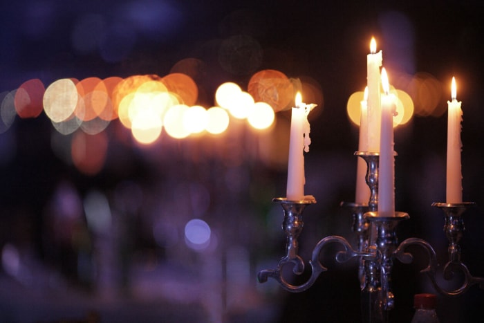 Chandelier rétro en métal avec cinq bougies allumées sur un fond sombre dans la pièce