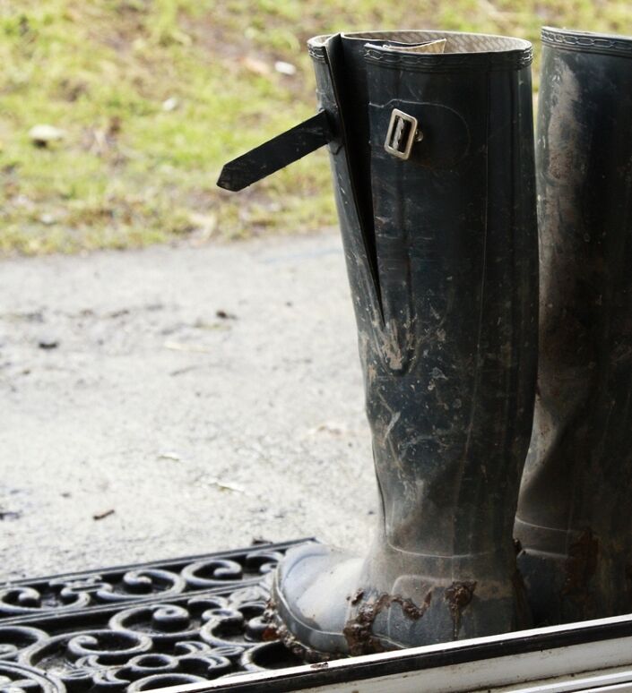 Paire de bottes noires boueuses près de la porte d'entrée.