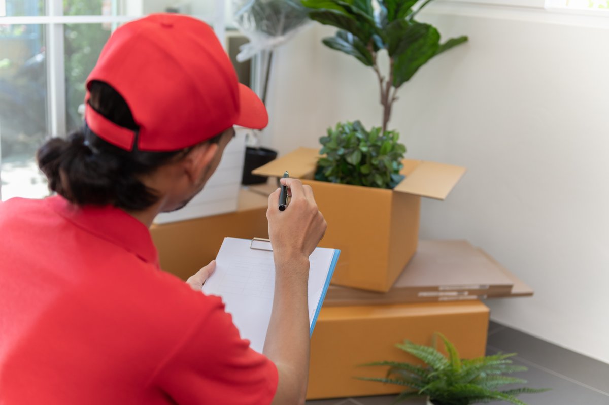 Un déménageur compte les cartons à marquer sur un presse-papiers.