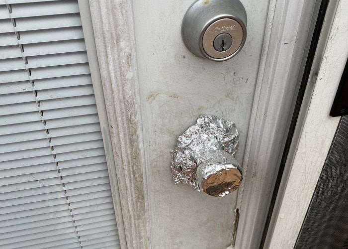 Une feuille d'aluminium recouvre une poignée de porte.