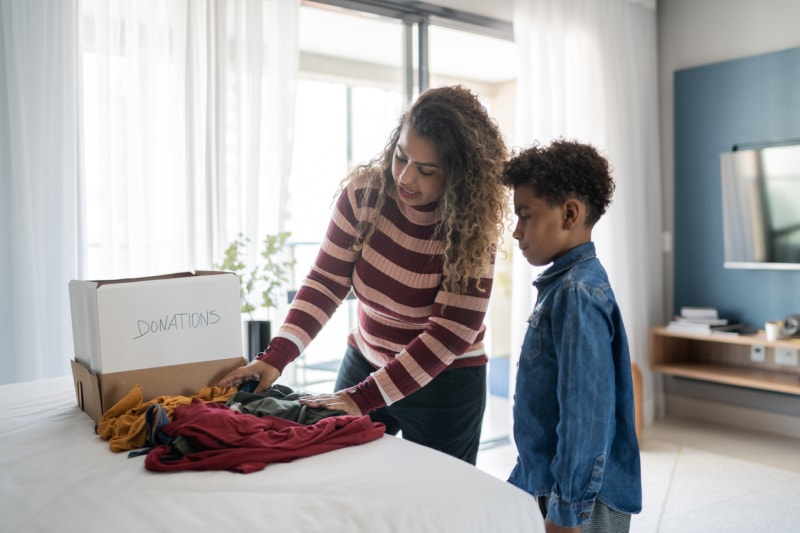 Une mère et son fils trient des vêtements à la maison pour les donner