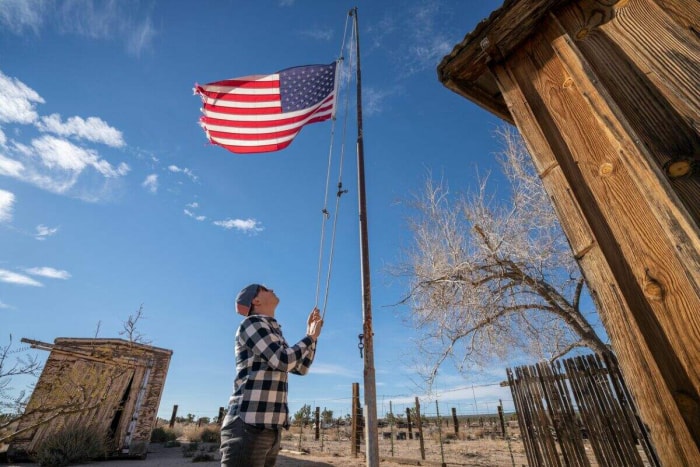 Un jeune homme hisse le drapeau américain sur un mât