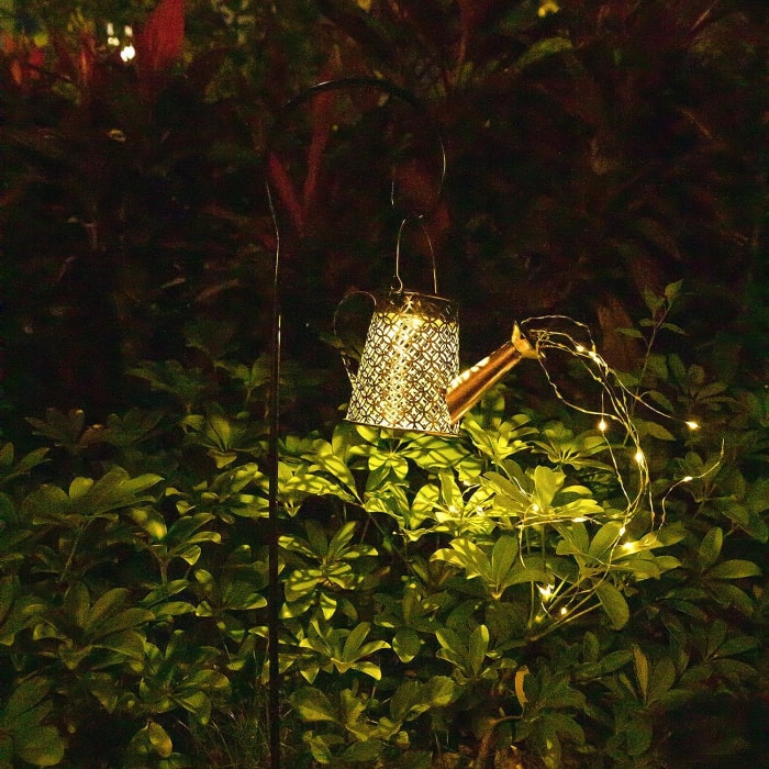 prise de vue nocturne d'un crochet lumineux en forme d'arrosoir avec des guirlandes lumineuses sortant du bec