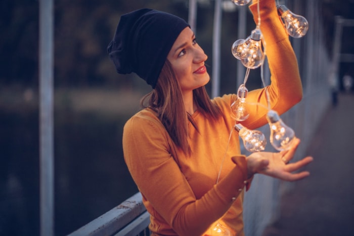 Femme regardant une guirlande lumineuse dans ses mains