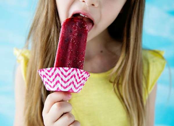 Fille mangeant un popsicle protégé par une doublure de cupcake