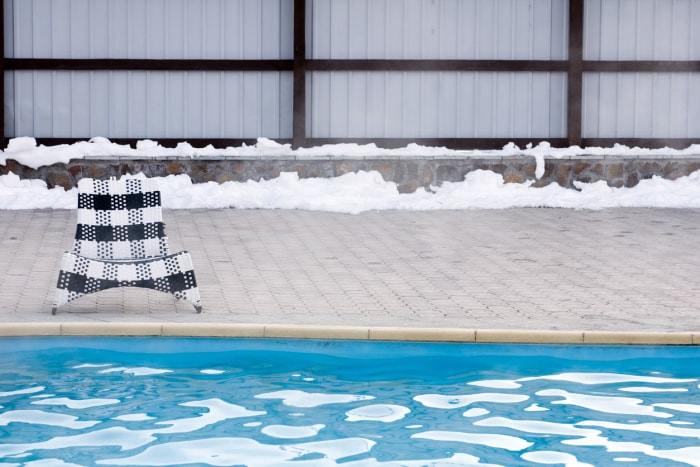 Une chaise à carreaux noirs et blancs assise au bord d'une piscine à glace flottante.