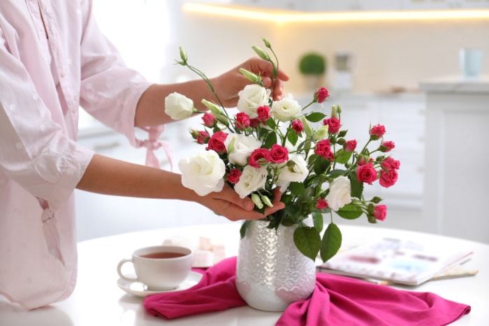 Femme retouchant des fleurs fraîches dans un vase