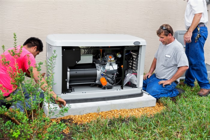 Plusieurs techniciens travaillant sur un générateur domestique.