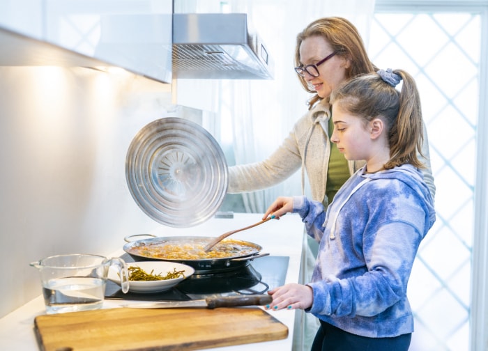 vue latérale de la mère et de la fille en train de cuisiner sur une cuisinière avec de la fumée dans la cuisine