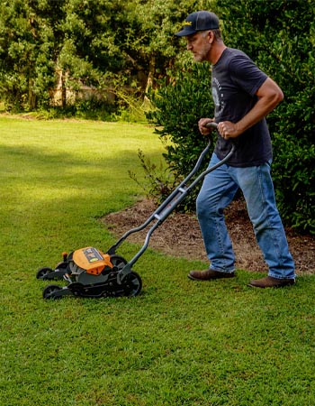 Une personne utilisant la tondeuse à bobine Fiskars StaySharp Max pour tondre sa pelouse