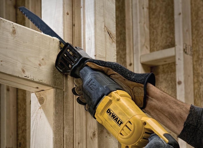 Une personne utilisant la meilleure scie alternative DeWalt pour couper une charpente dans une maison