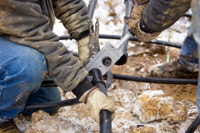 Crédit d'impôt pour l'amélioration de l'efficacité énergétique de l'habitat - Mains d'ouvriers posant des tuyaux pour un système géothermique