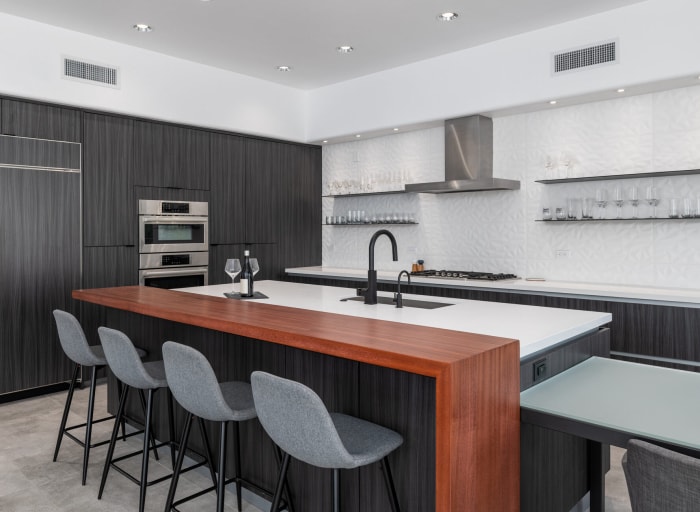 Un îlot de cuisine moderne avec une surface de comptoir en quartz et une surface de bar en bois.