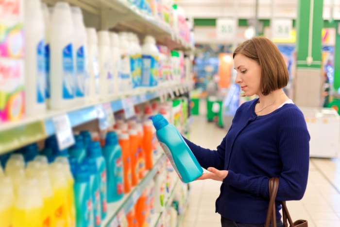 Une femme regarde une lessive dans un magasin