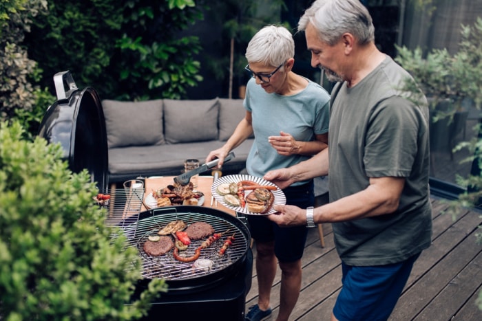 Couple de seniors cuisinant sur un gril à l'extérieur