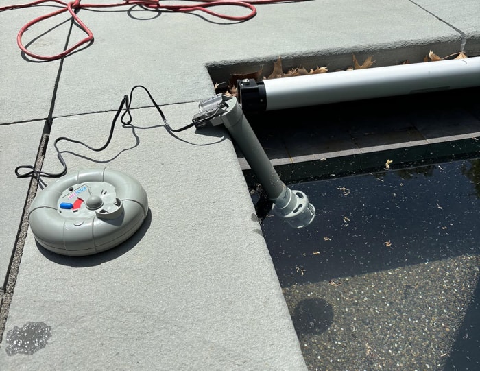 L'alarme de piscine hors sol PoolEye sur une terrasse de piscine et flottant dans une piscine.