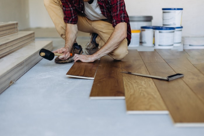 Une-personne-utilise-un-mallet-pour-réparer-un-parquet-en-planche-de-vinyle.