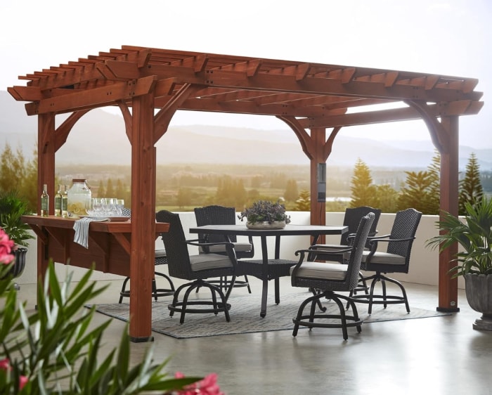 Pergola en bois foncé avec table et sièges pour les repas en plein air.