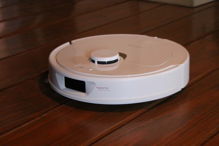 Un robot circulaire blanc nettoie le parquet