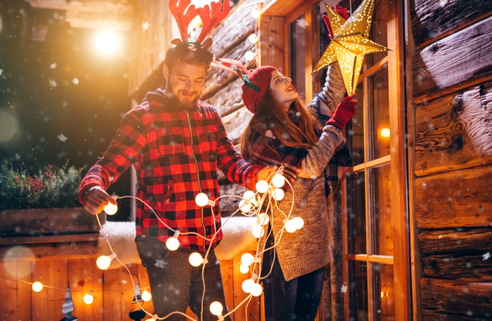 iStock-615632932 à faire en décembre couple accrochant des lumières de Noël à l'extérieur