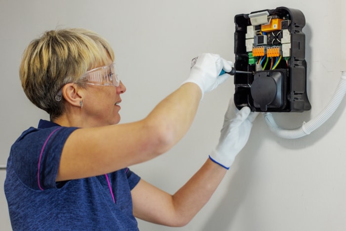 Une personne installant un chargeur de véhicule électrique dans le garage d’une maison.