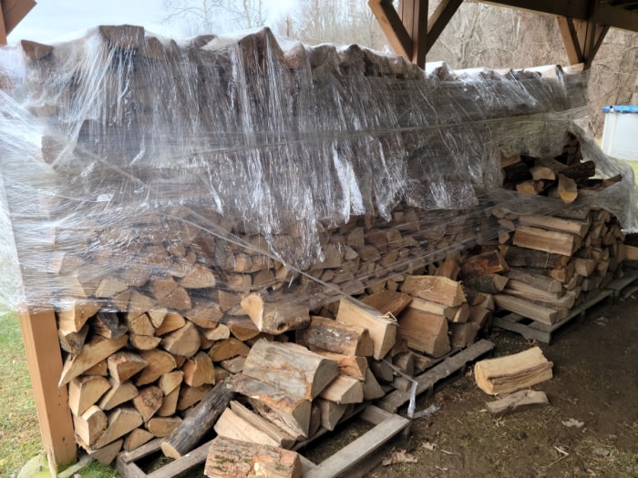 Grande pile de bois de chauffage enveloppée de plastique partout.