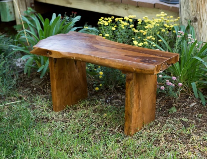 Un banc de jardin en teck entouré de fleurs de jardin.