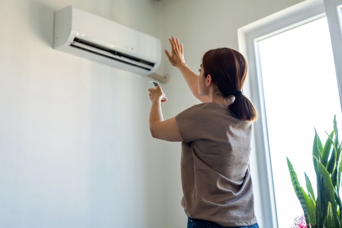 femme allumant l'unité de climatisation mini split pour une meilleure efficacité énergétique