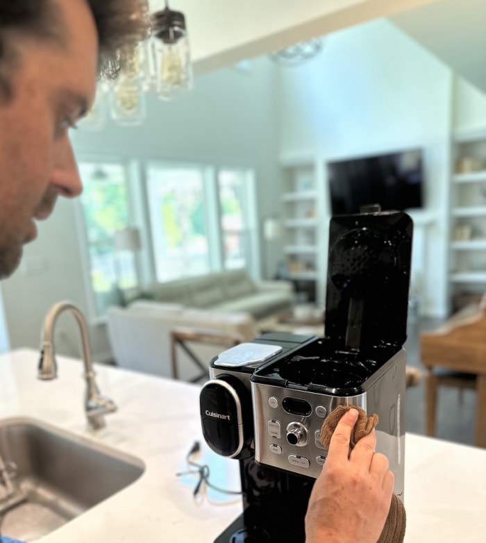 Un homme nettoie l'extérieur d'une cafetière Cuisinart