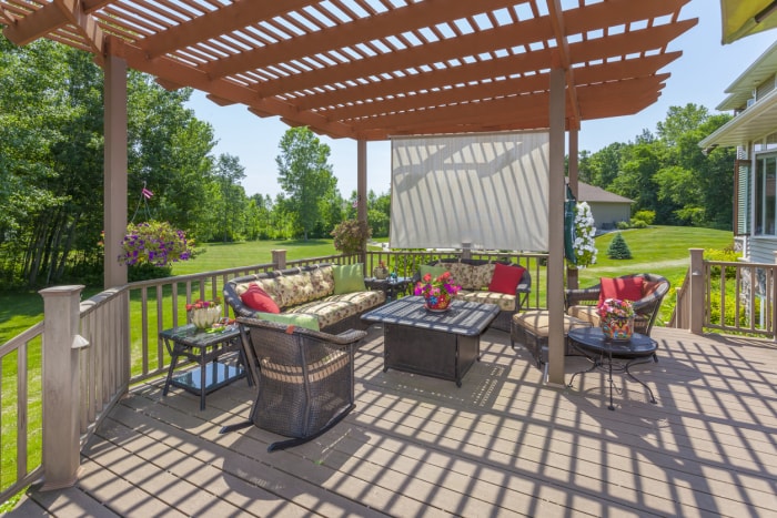 Pergola extérieure avec parasol et mobilier de terrasse. .