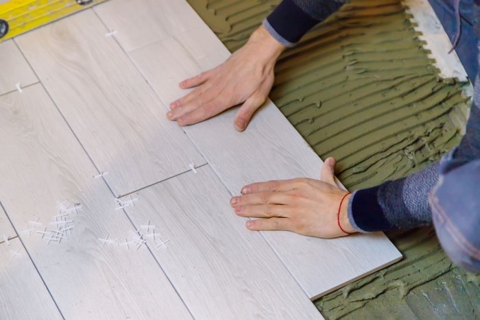 Artisan expert installant un plancher de bois d'ingénierie dans une maison résidentielle, mettant en valeur la texture et la qualité du matériau.