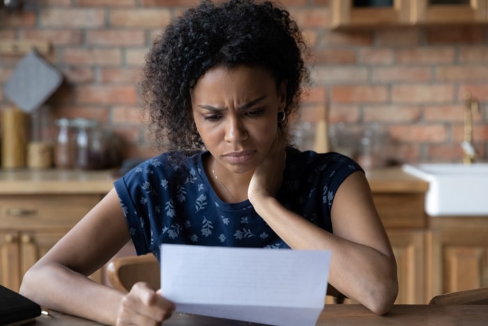 Jeune femme regardant une lettre en fronçant les sourcils