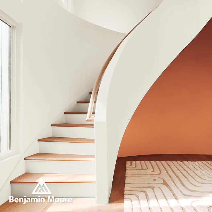 Un escalier peint avec White Dove de Benjamin Moore est compensé par un mur d'accent orange.