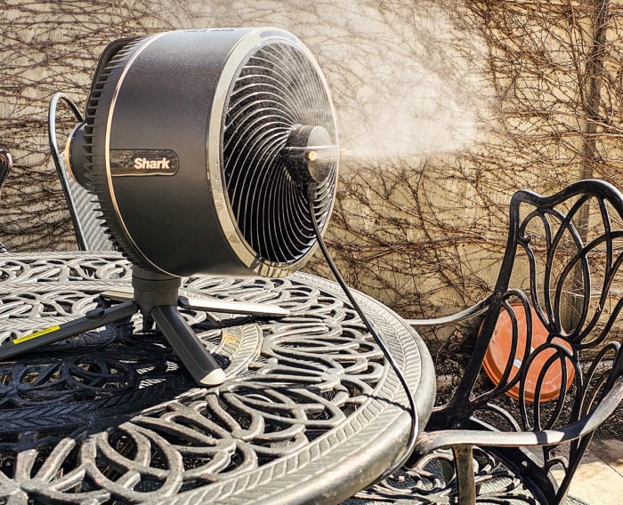 Le ventilateur Shark FlexBreeze avec InstaCool installé sur une table de patio pendant les tests et soufflant une brume fraîche dans l'air.