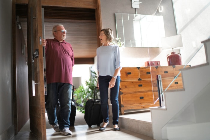 Couple de personnes âgées rentrant à la maison avec des bagages