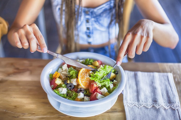 Jeune femme mangeant une salade au restaurant, seule.