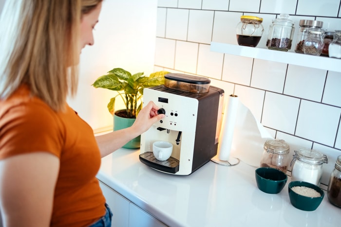 Jeune femme faisant du café sur une machine à café à la maison