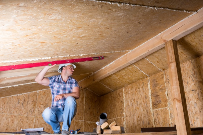 L'entrepreneur tient un niveleur sur le plafond pour planifier l'installation d'un puits de lumière.