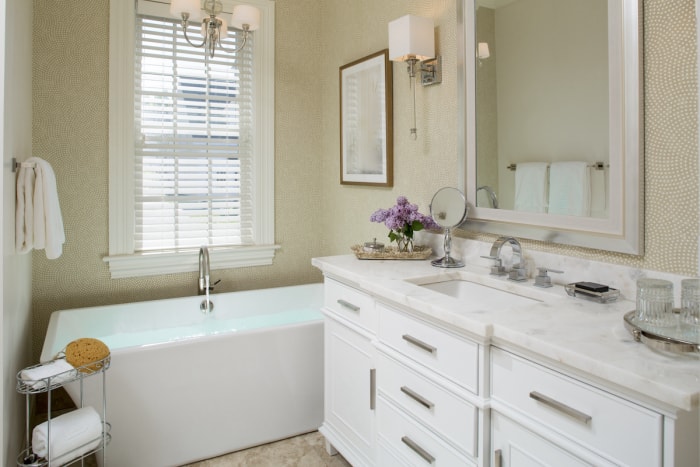 Une salle de bain avec du papier peint à pois et une vanité en bois blanc.