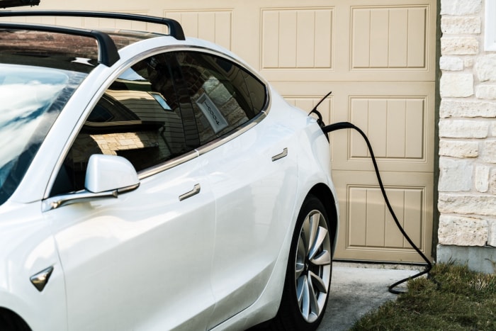 Un véhicule électrique en charge dans l'allée d'une maison.