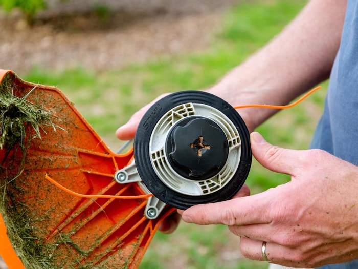 Personne tenant une bobine de fil de coupe-herbe sur une débroussailleuse à batterie Stihl FSA 80 R