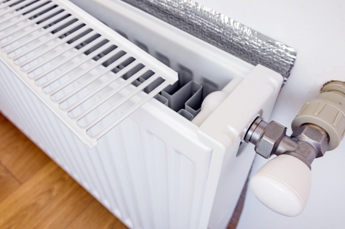 Radiateur avec grille retirée et feuille derrière.