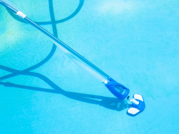 Le meilleur aspirateur à main sur une perche extensible avec un tuyau attaché et utilisé pour nettoyer le fond d'une piscine.