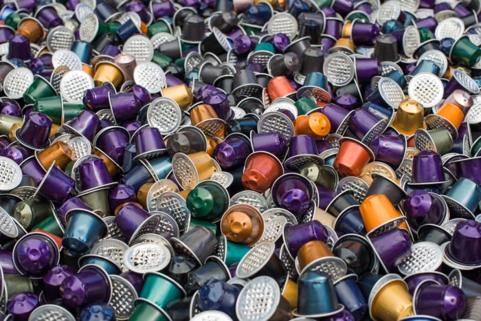 Vue rapprochée d'une pile de dosettes Nespresso usagées de différentes couleurs.